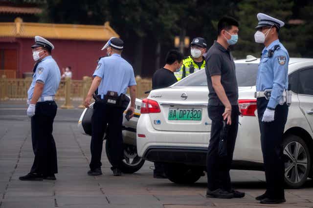 <p>Police officers talk to a man in a street close to Tiananmen Square in Beijing</p>