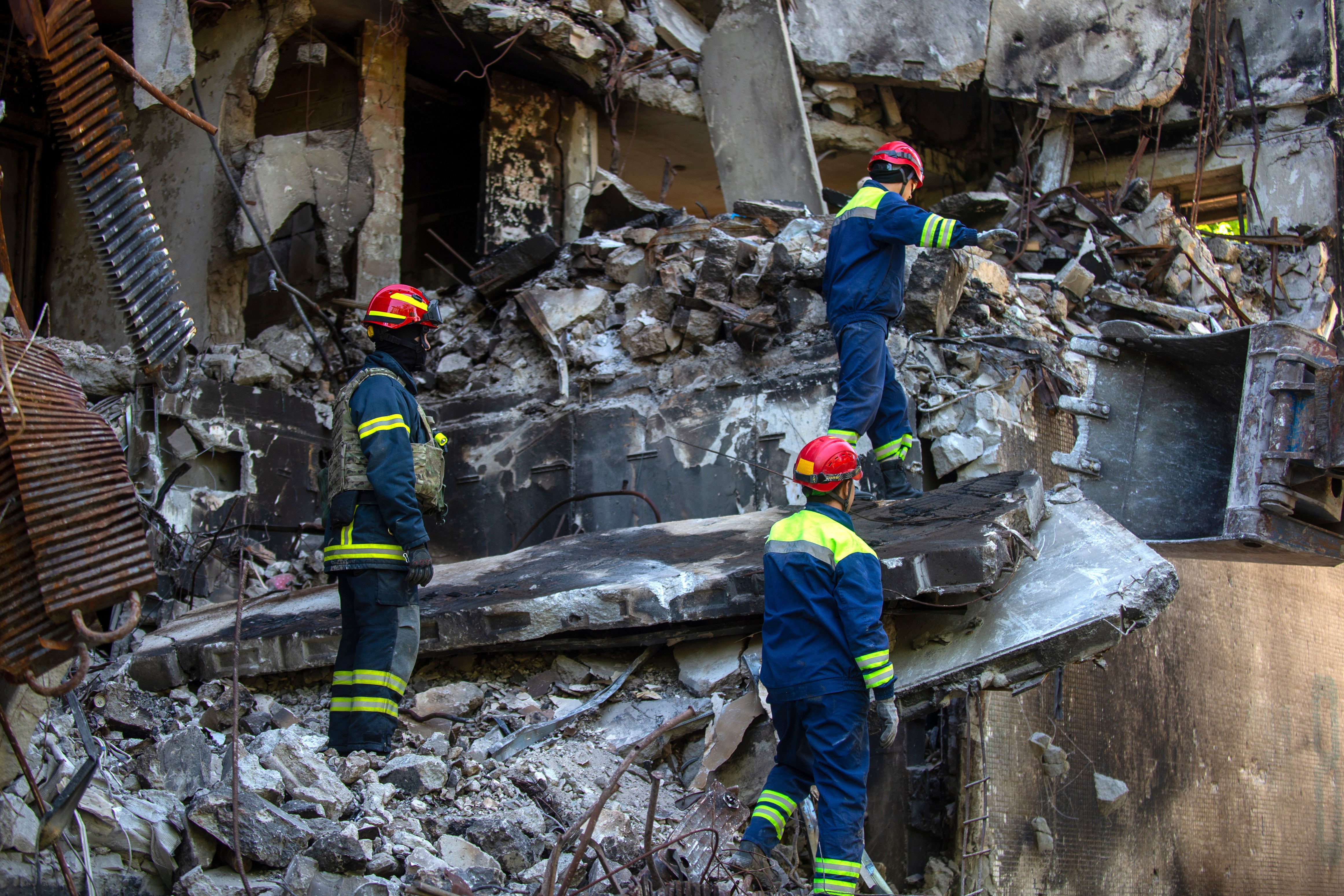 Ukrainian emergency service personnel work outside a damaged building following shelling in Kharkiv