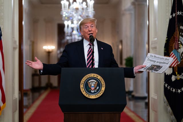 <p>President Donald Trump holds up a newspaper with a headline that reads ‘Trump acquitted’ </p>