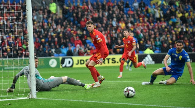 <p>Wales defenders watch as the ball runs wide</p>