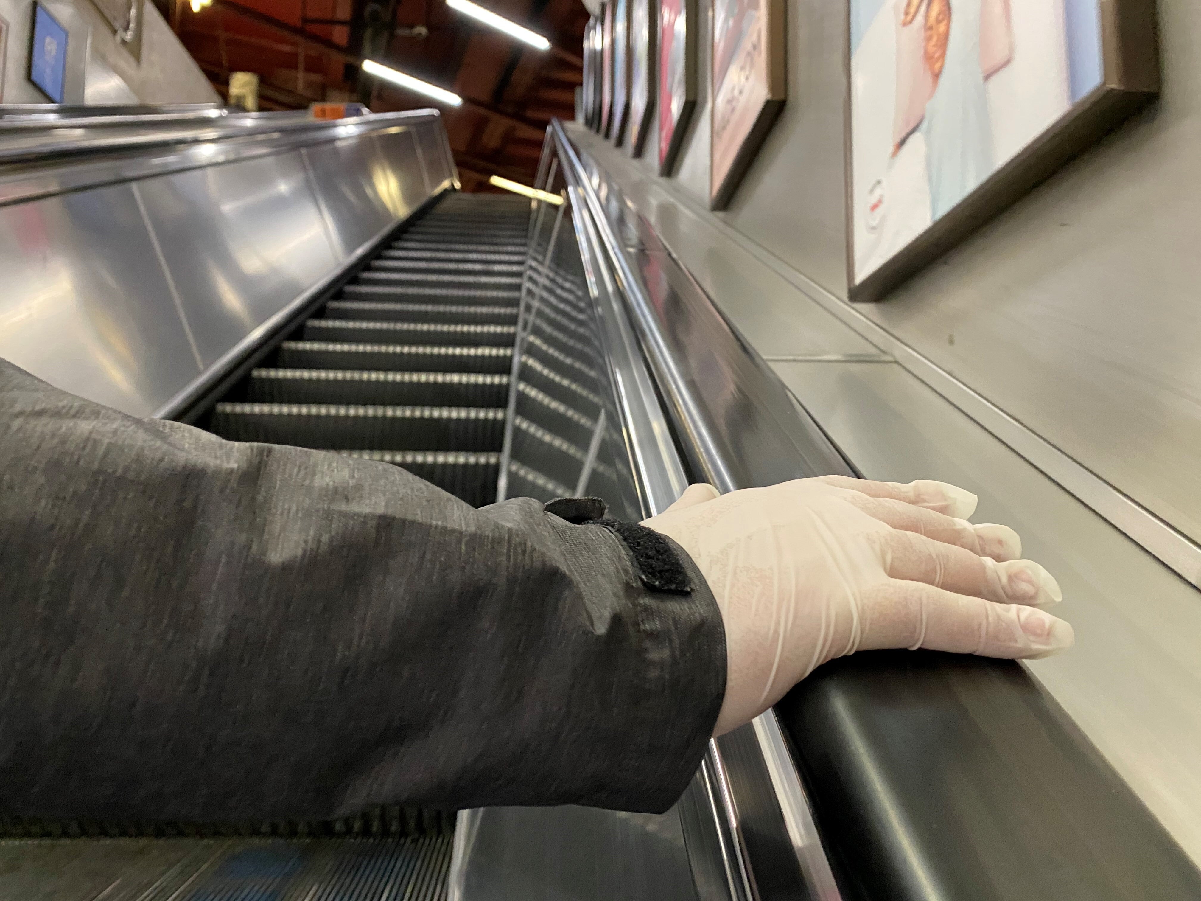 A person with a gloved hand uses an escalator in Baker Street Underground Station in London (Luciana Guerra/PA)