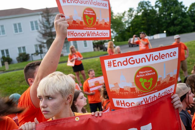 <p>People hold up signs during a rally for National Gun Violence Awareness Day on 3 June</p>