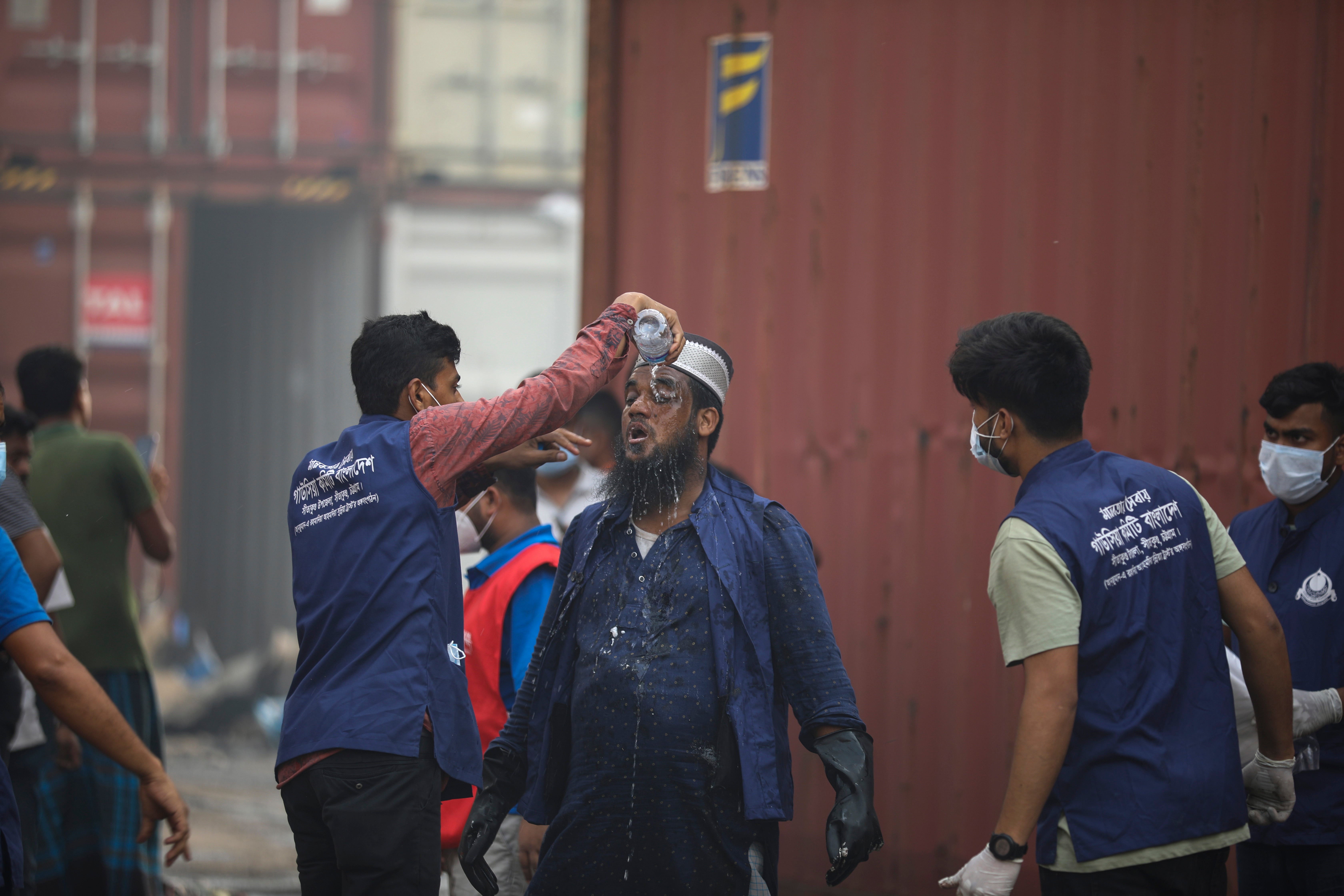 A rescuer pours water on the face of another after a fire broke out at the BM Inland Container Depot