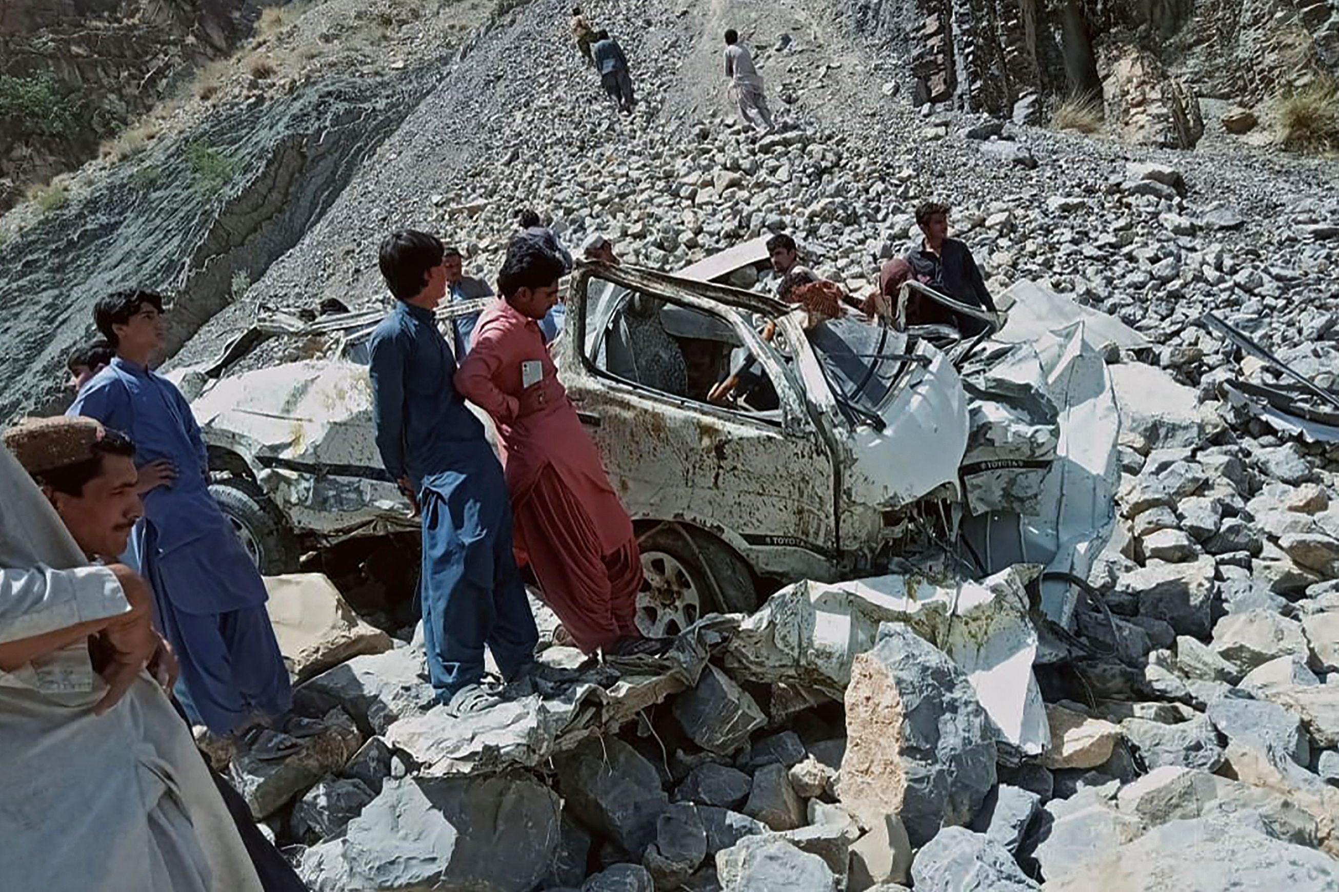Onlookers gather around the wreckage of a passenger vehicle that plunged into a deep ravine in Qila Saifullah district of Balochistan province on 8 June 2022
