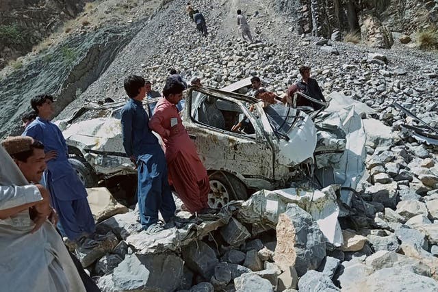 <p>Onlookers gather around the wreckage of a passenger vehicle that plunged into a deep ravine in Qila Saifullah district of Balochistan province on 8 June 2022</p>