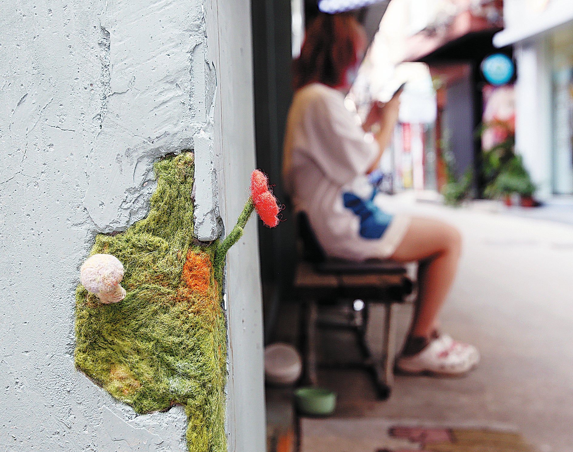 A flower and a mushroom made of felt are installed in a broken wall in Nanting village in Guangzhou
