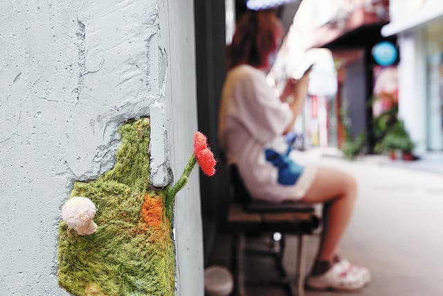 <p>A flower and a mushroom made of felt are installed in a broken wall in Nanting village in Guangzhou</p>