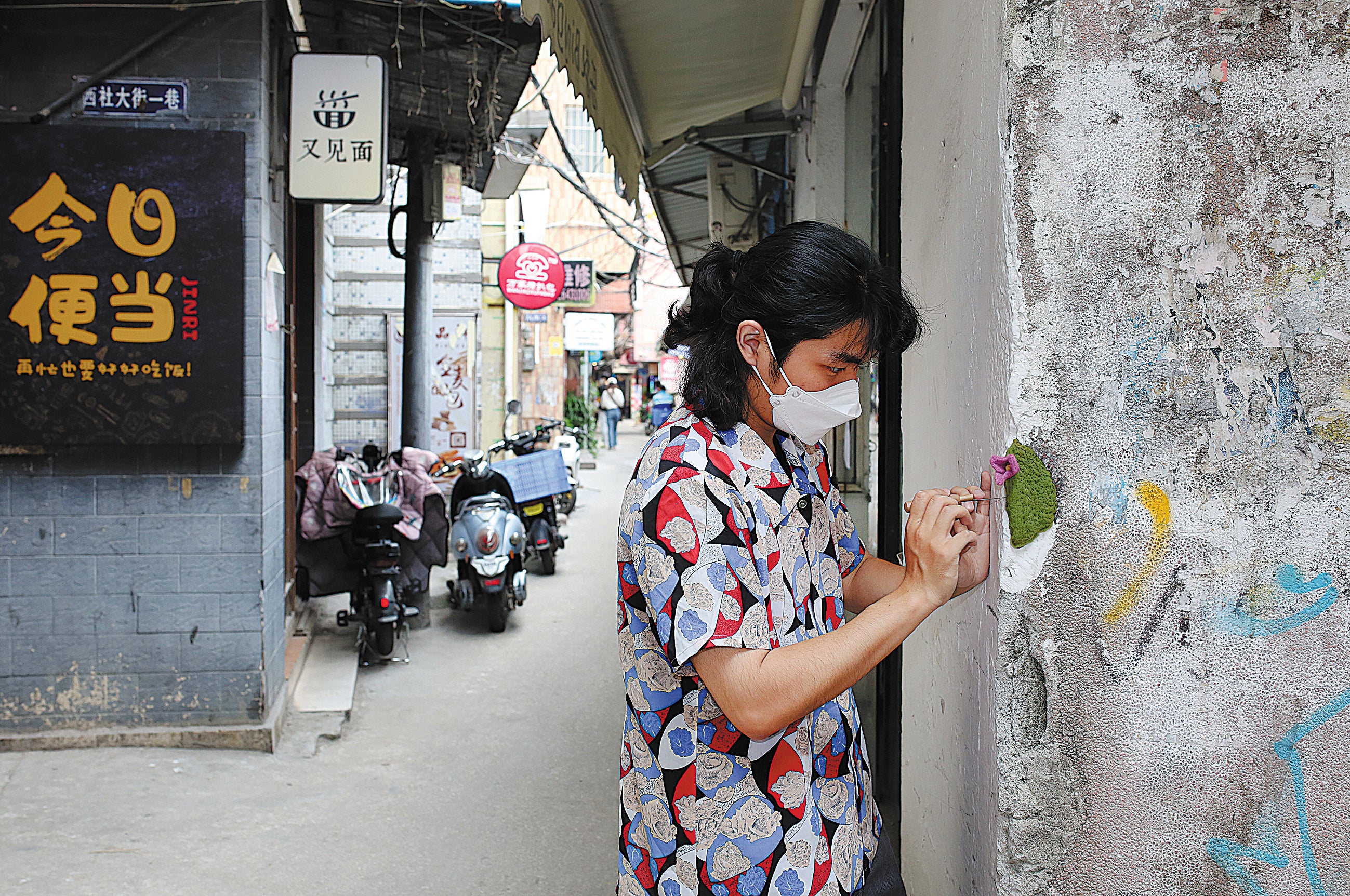 Luo Shengtian places a felt flower in the broken corner of a wall in the village