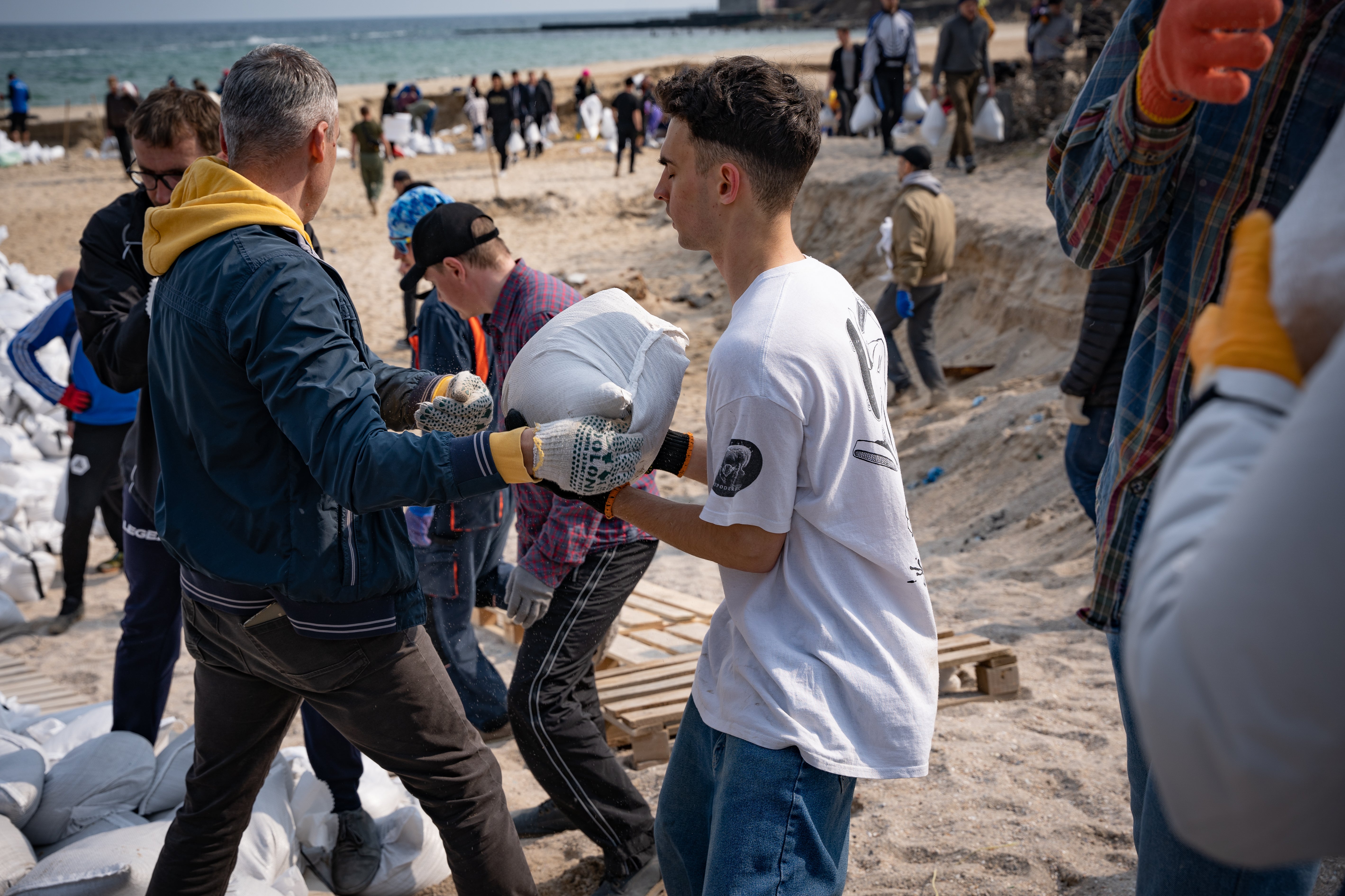 Volunteers on Odesa’s beaches moving sandbags to send to the front