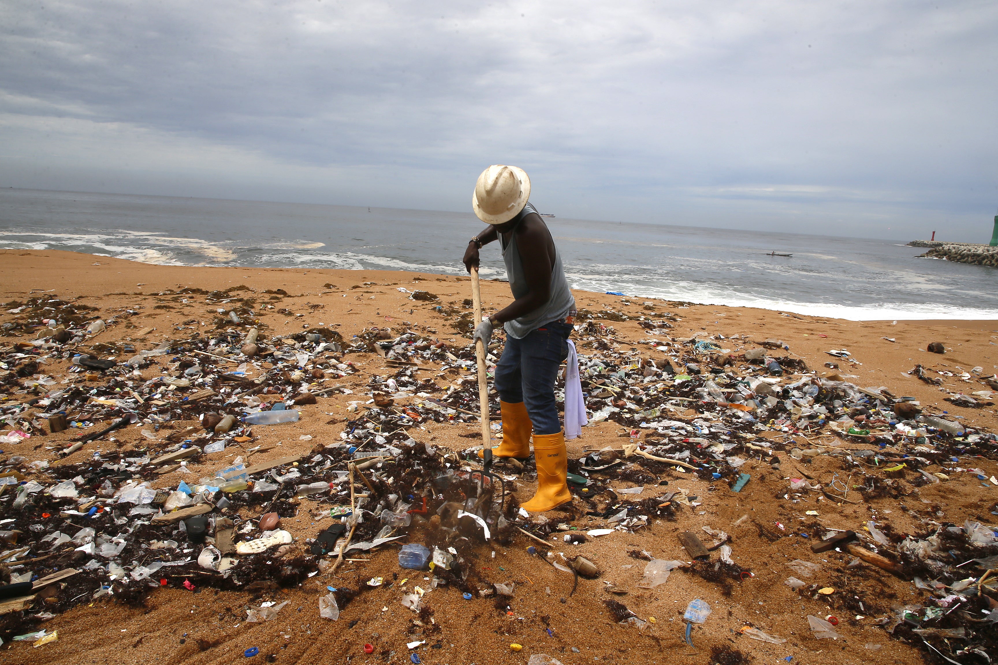 A member of an environmental NGO cleans plastic debris from Vridi beach in Abidjan, Ivory Coast