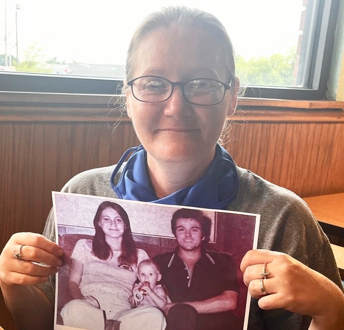 Baby Holly, now 42, holds a picture of herself as a baby with her murdered parents after being informed this week by investigators about her biological family