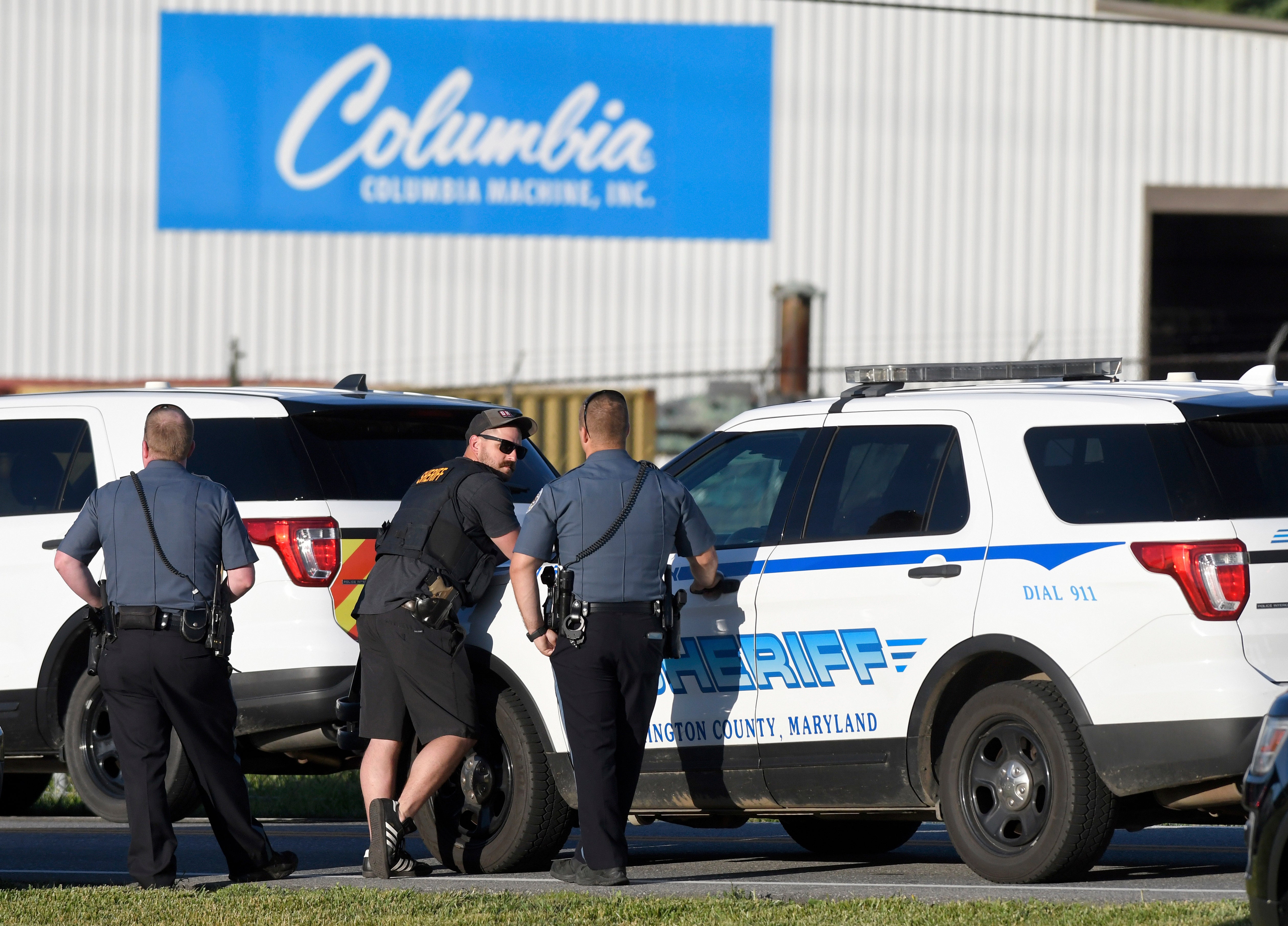Police stand near where a man opened fire at a business, killing three people before the suspect and a state trooper were wounded in a shootout, according to authorities, in Smithsburg, Md., Thursday, June 9, 2022. The Washington County (Md.) Sheriff's Office said in a news release that three victims were found dead at Columbia Machine Inc. and a fourth victim was critically injured.