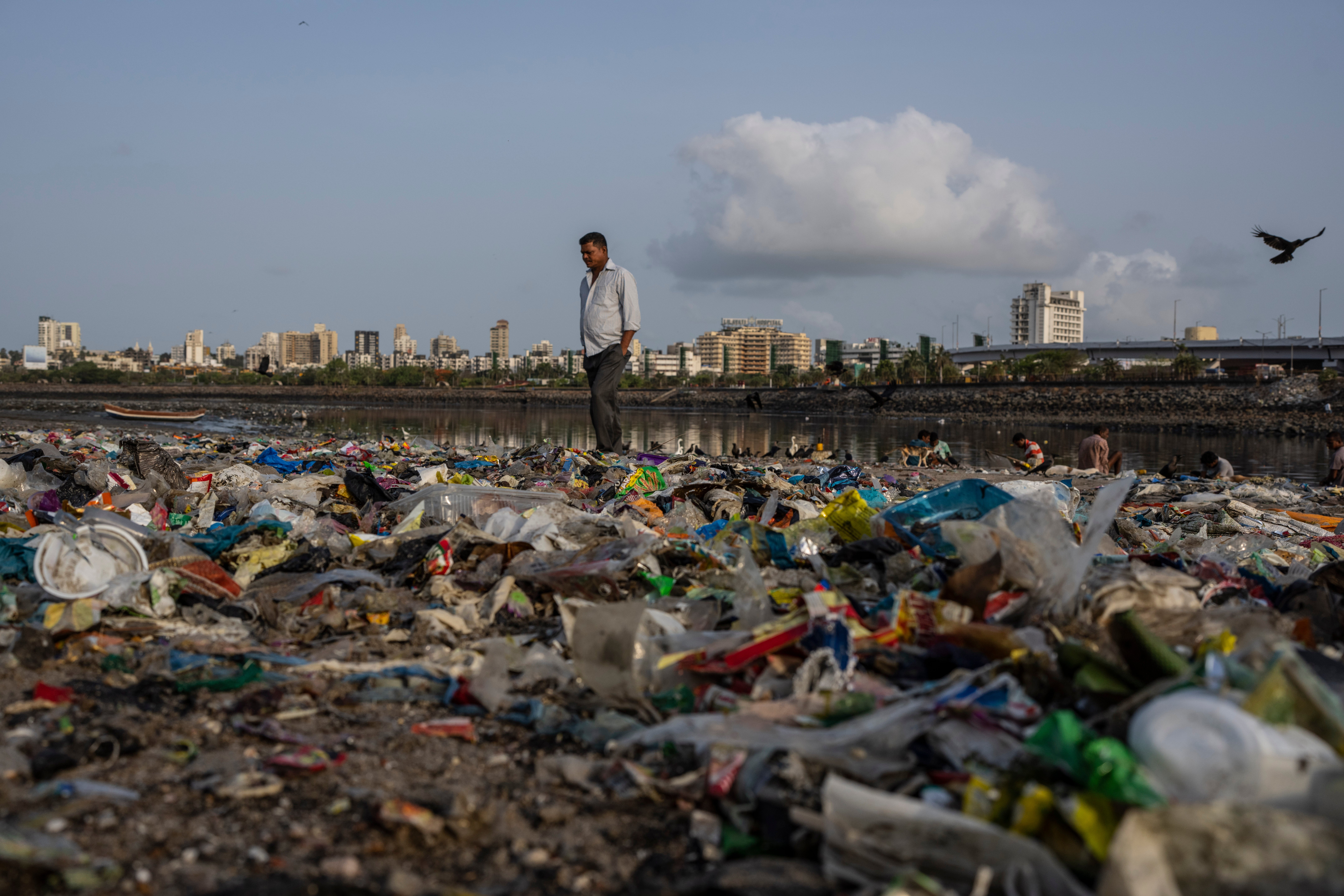 A man walks past plastic and other garbage littering the shores of the Arabian Sea in Mumbai on World Environment Day