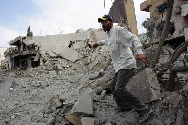 <p>A Lebanese man runs to prevent photographers from taking pictures of a Hezbollah building destroyed in an Israeli airstrike in Qana</p>