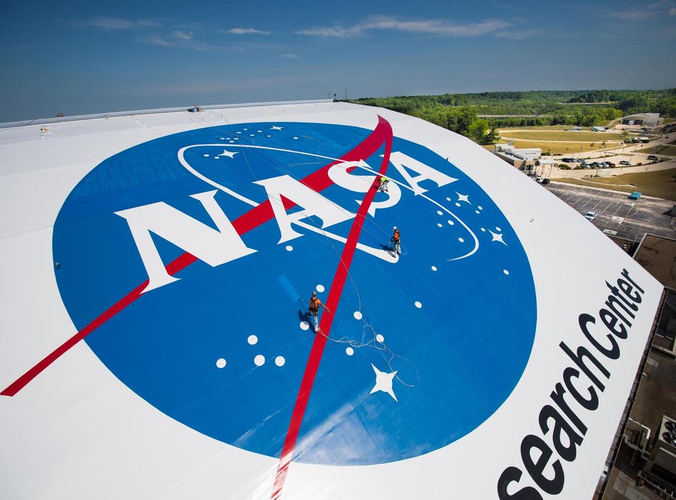 <p>Workers paint the Nasa logo on a building at Nasa’s Glenn Research Center</p>