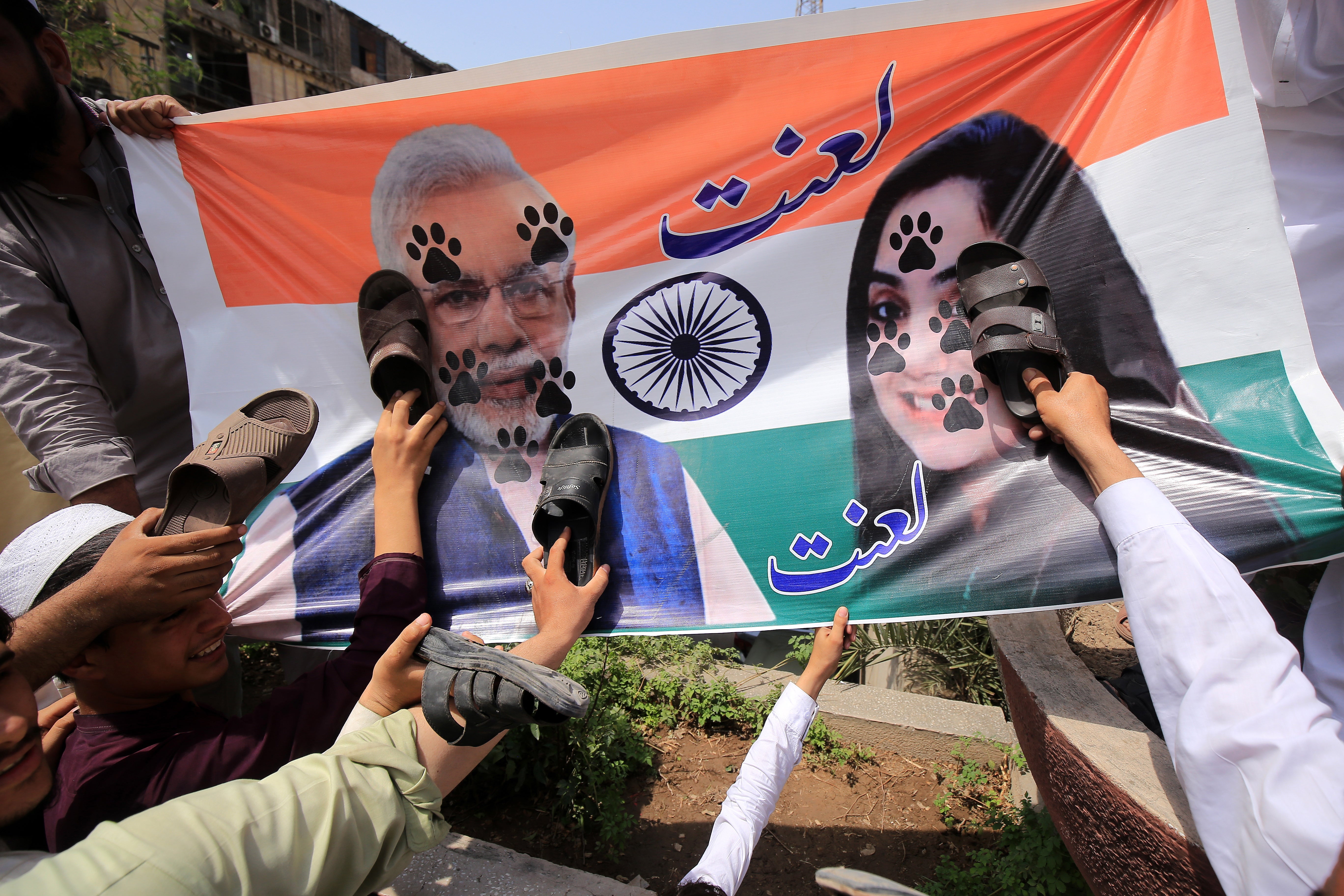 Supporters of Muttahida Shariat Mahaz Pakistan conservative party hold their shoes against a banner depicting Indian prime minister Narendra Modi (left) and former BJP spokesperson Nupur Sharma (right) during a protest in Pakistan’s Peshawar city on 10 June