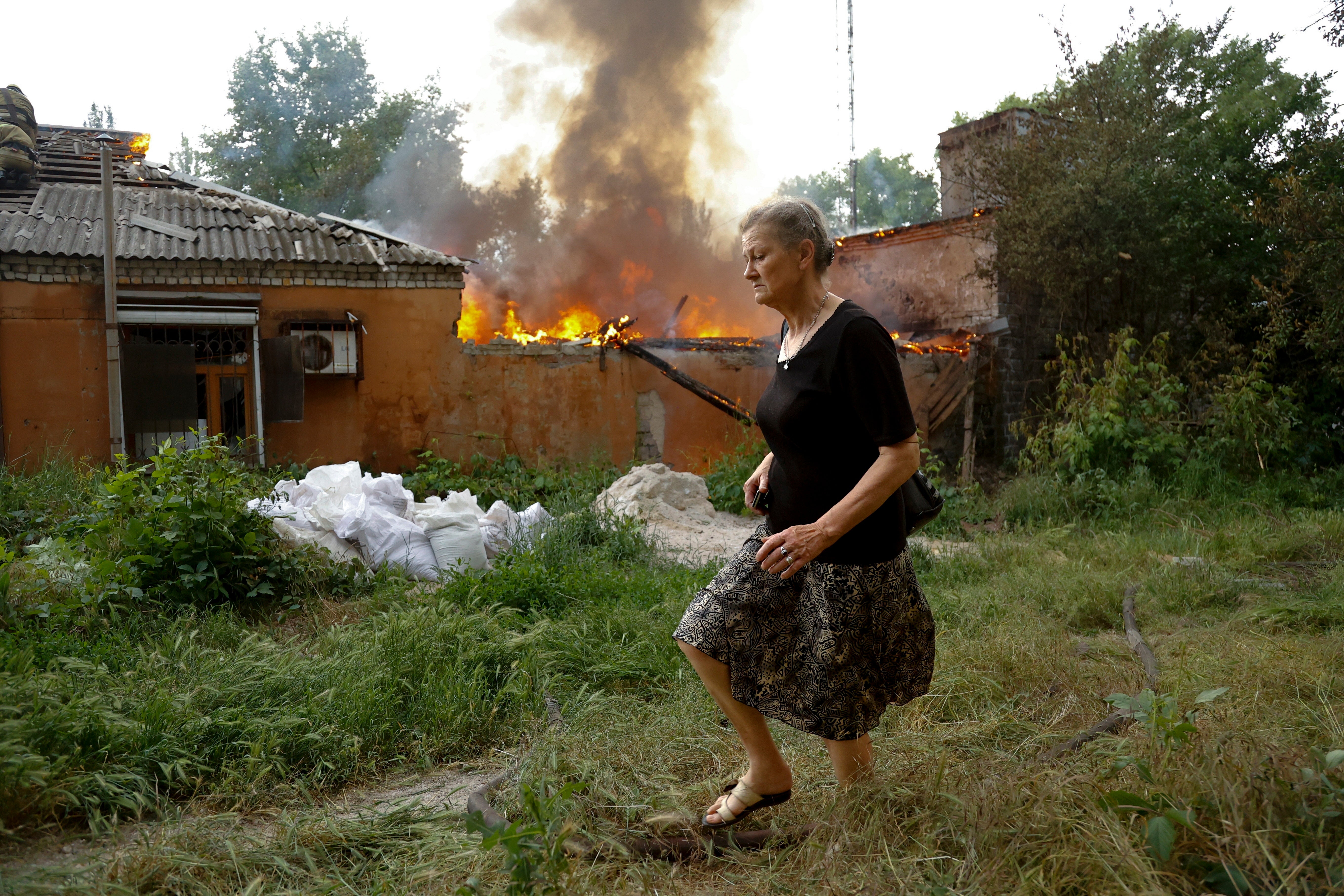 A woman runs from a house on fire after shelling in Donetsk