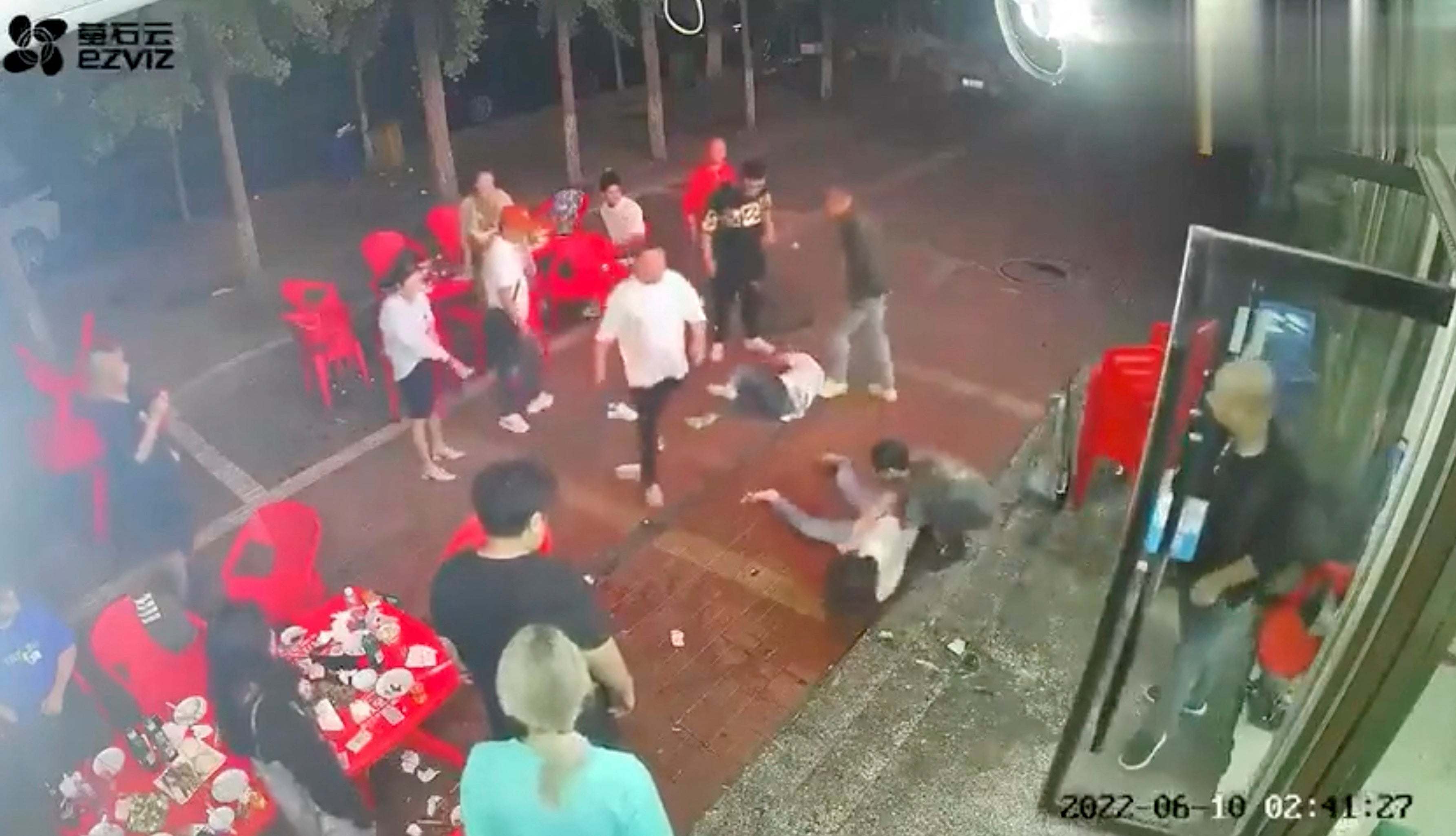 Two women lie on the ground after being assaulted by a group of men outside a restaurant in the northeastern city of Tangshan