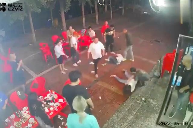 <p>Two women lie on the ground after being assaulted by a group of men outside a restaurant in the northeastern city of Tangshan</p>