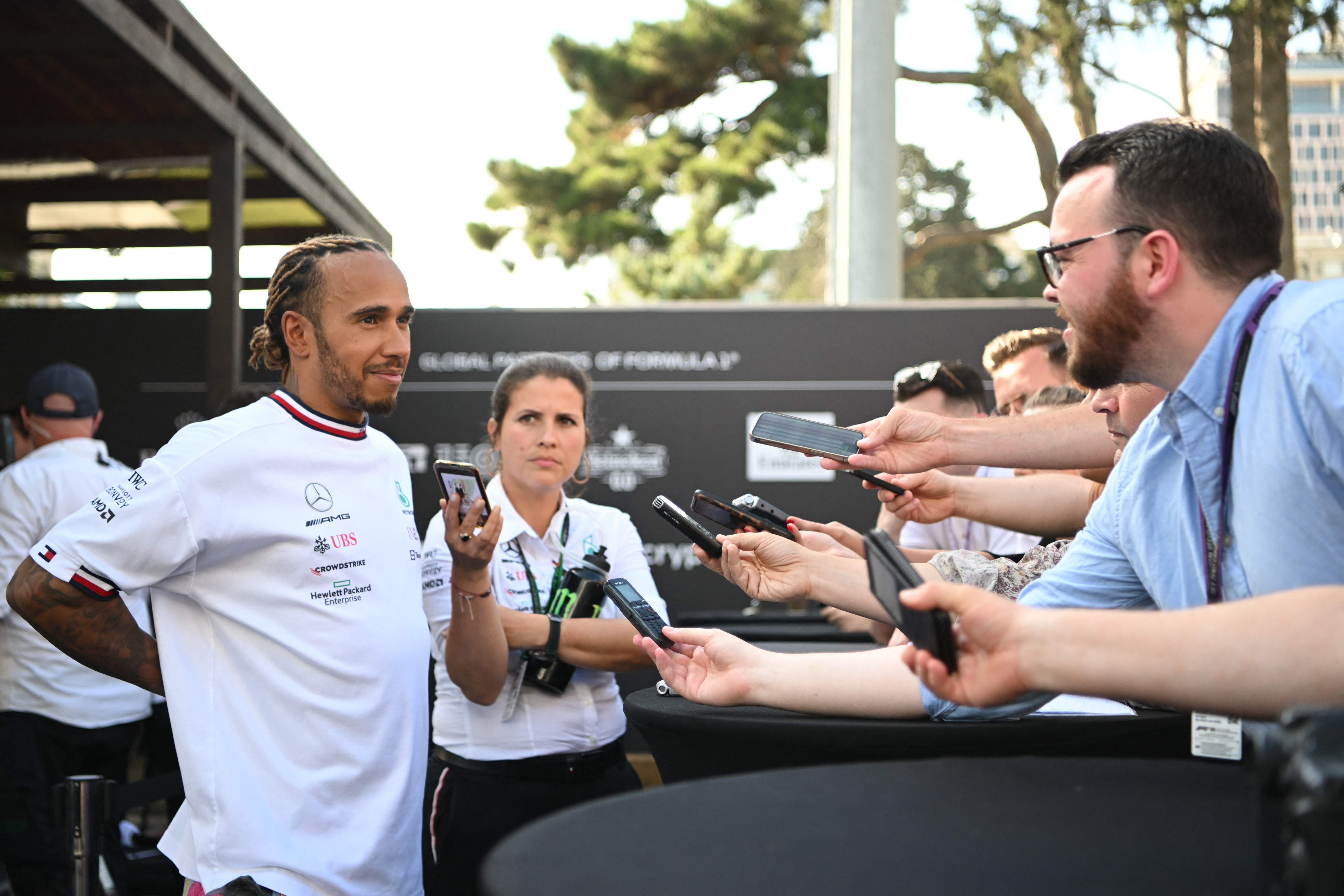 Lewis Hamilton holds his back as he talks to the media