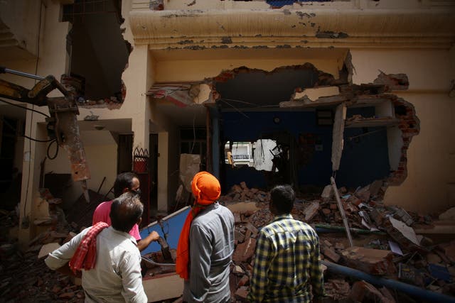 <p>People watch as a bulldozer demolishes the house of a Muslim man in Uttar Pradesh</p>