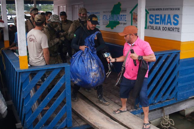 <p>A police officer carries a bag containing items recovered by a search party near Atalaia do Norte</p>