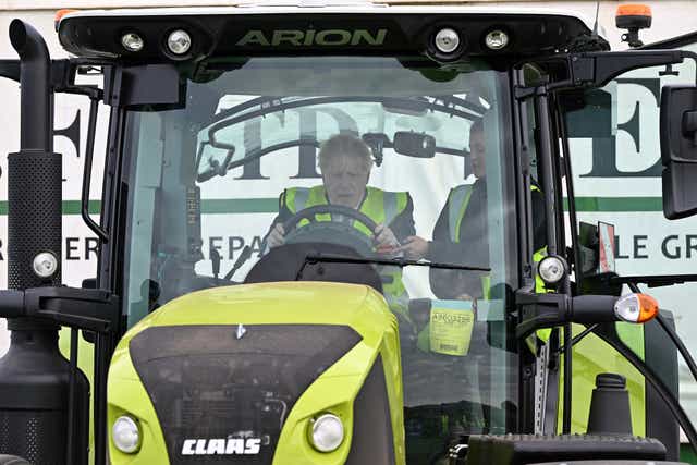 Prime Minister Boris Johnson is instructed as he drives a tractor during a visit to Southern England Farms Ltd in Hayle, Cornwall, ahead of the publication of the UK government’s food strategy white paper, Cornwall. Picture date: Monday June 13, 2022 (Justin Tallis/PA)