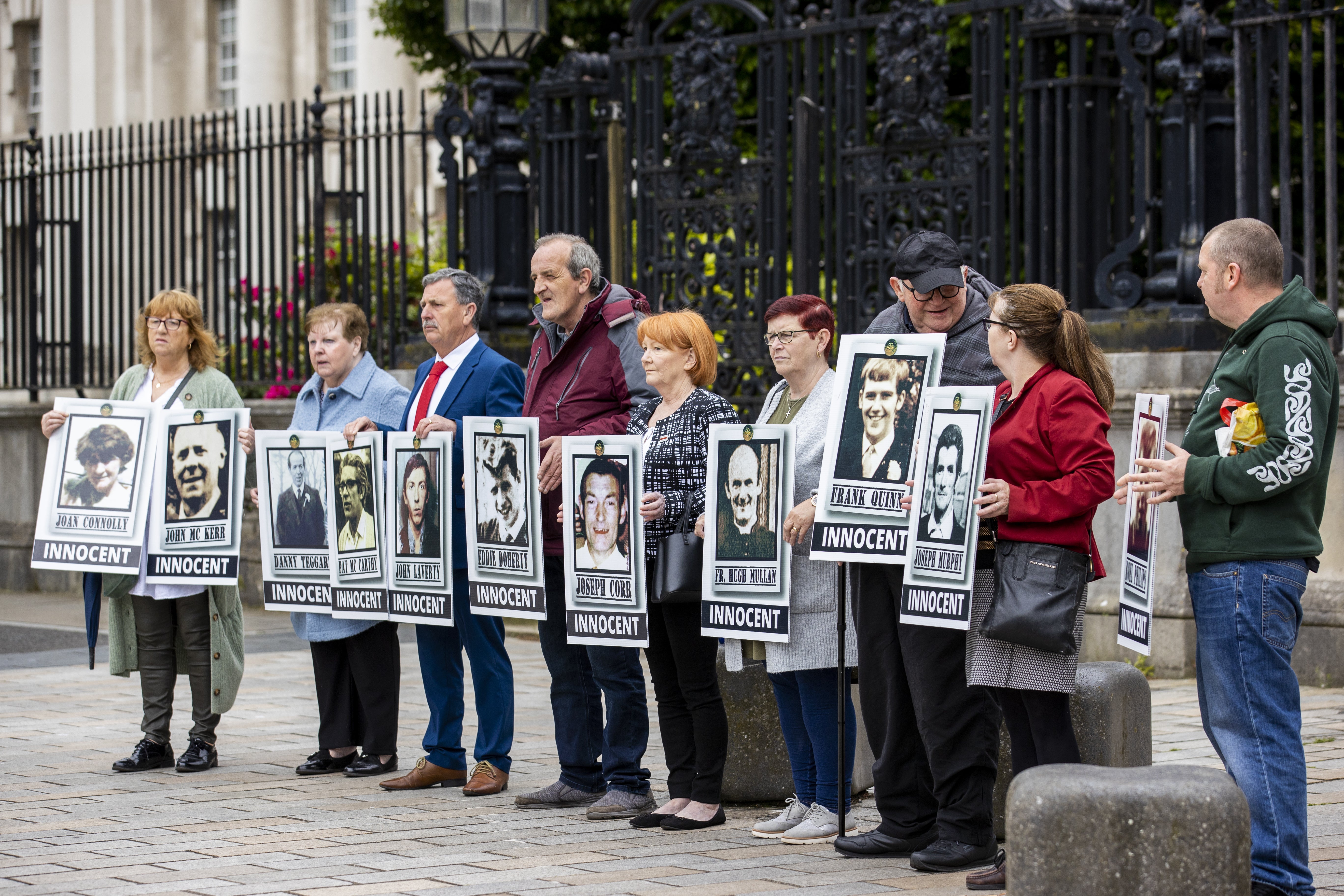 Families of those killed during the Ballymurphy Killings stand holding images of loved ones outside The High Court in Belfast (Liam McBurney/PA)