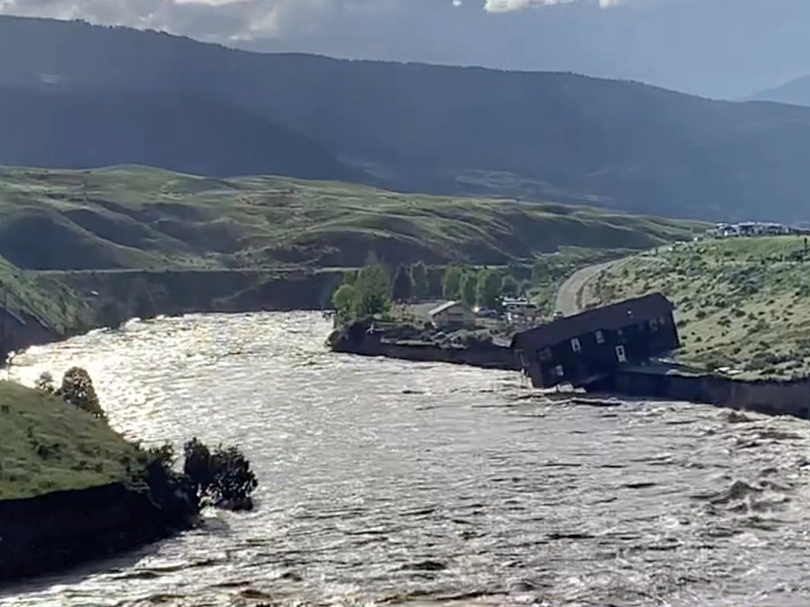 A house falls into the Yellowstone river due to flooding in Gardiner, Montana, U.S., June 13, 2022 in this screen grab obtained from a social media video