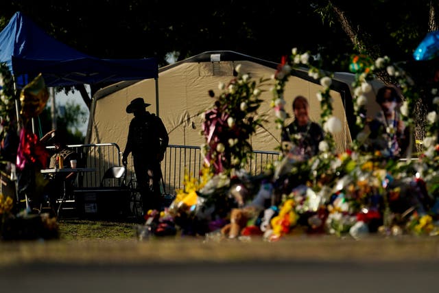 Un oficial del Departamento de Seguridad Pública de Texas vigila el 3 de junio de 2022 en Uvalde, Texas, cerca de un monumento fuera de la Escuela Primaria Robb creado para honrar a las víctimas muertas en el último tiroteo en una escuela.