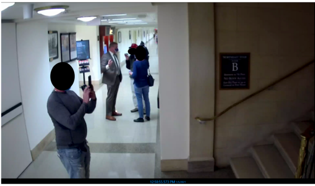 Un miembro de un grupo turístico encabezado por el representante de Georgia, Barry Loudermilk, fotografía una escalera en el edificio de oficinas de Longworth House mientras el Sr. Loudermilk (al fondo) habla con otros dos