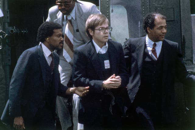 <p>FILE - U.S. Marshalls escort John Hinckley Jr. as he returns to a marine base via helicopter in Quantico, Va., Aug. 8, 1981.</p>
