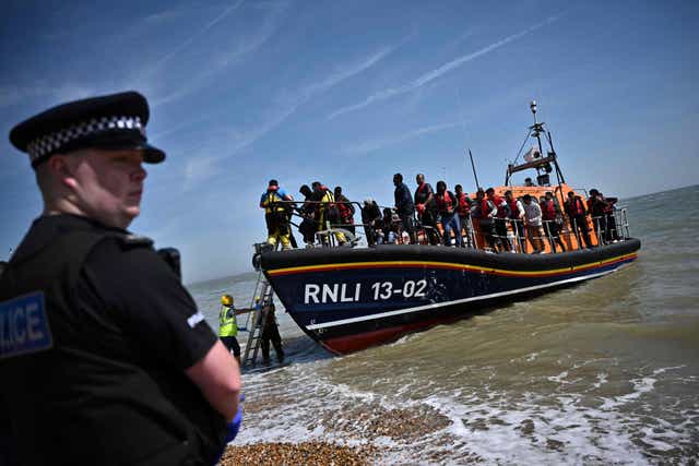 <p>Royal National Lifeboat Institution's (RNLI) members of staff help migrants to disembark from one of their lifeboats after they were picked up at sea while attempting to cross the English Channel</p>
