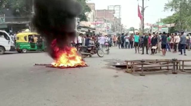 <p>Demonstrators surround burning tyres on a street in Jehanabad, Bihar, as they protest against the new scheme to recruit military personnel</p>
