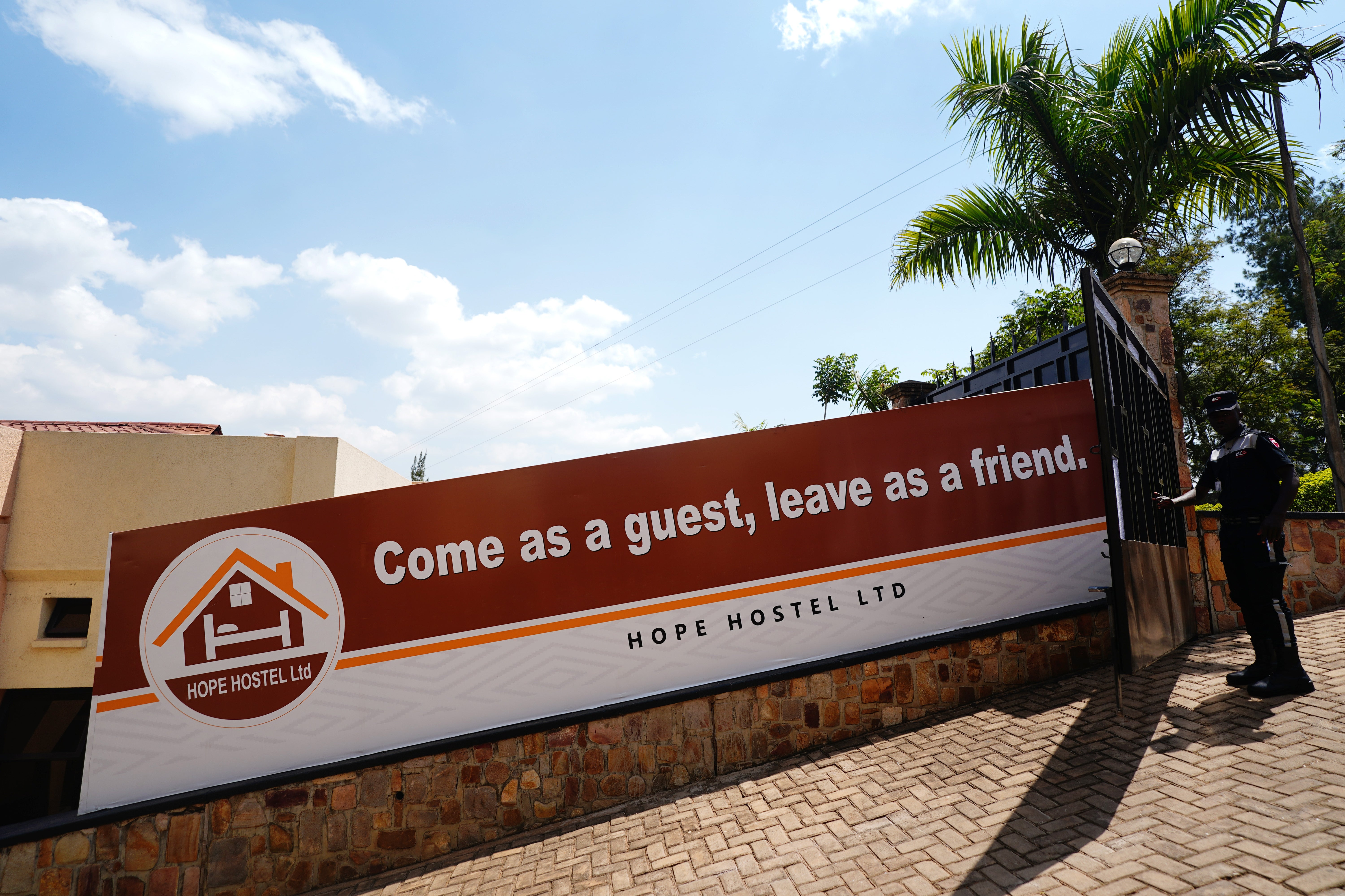 A security guard opens the entrance gate next to a sign reading ‘Come as a guest, leave as friend’ (Victoria Jones/PA)
