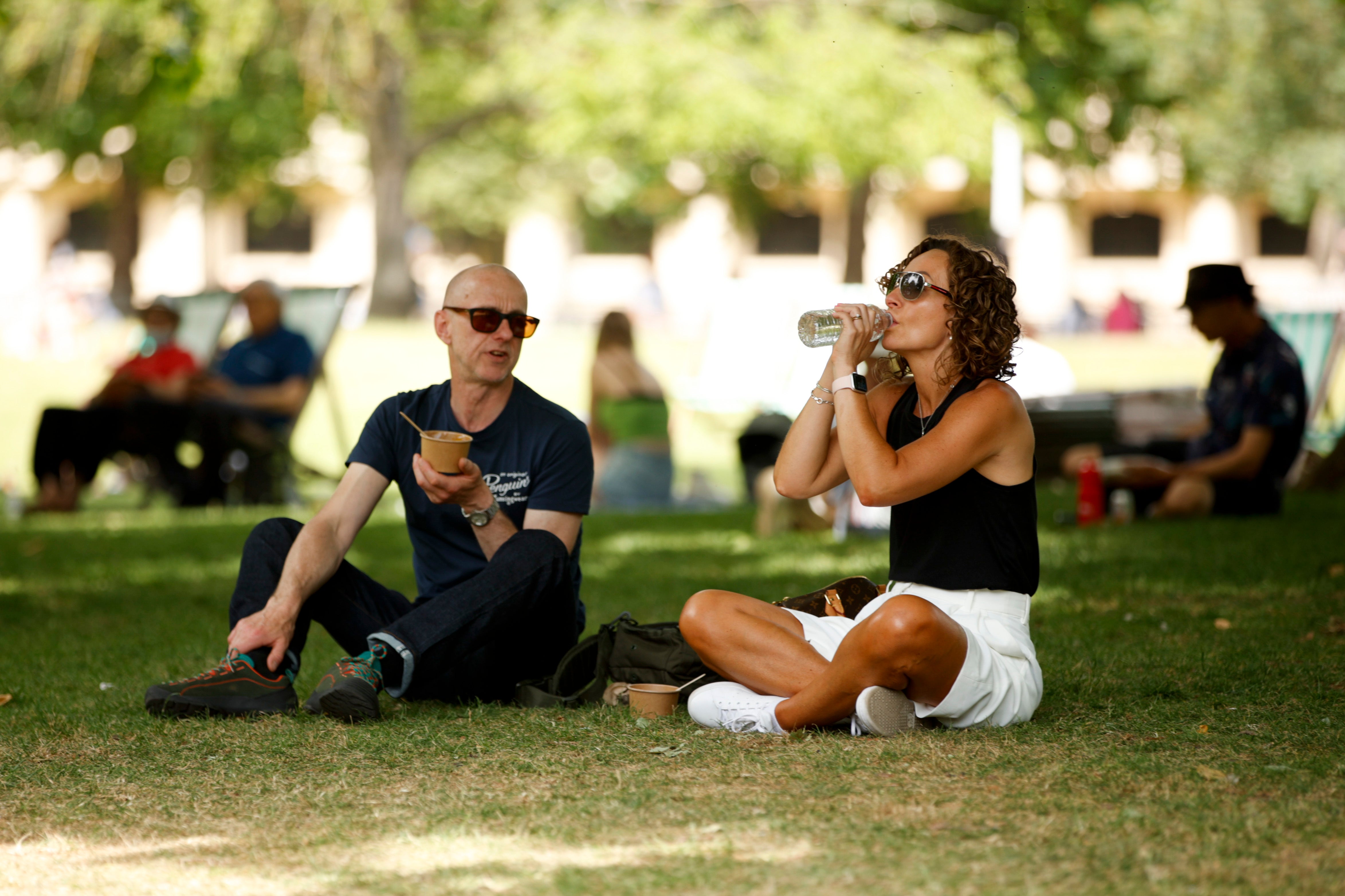 A man and woman picnic in the shade of a tree in hot weather in St James’s Park in London on Thursday