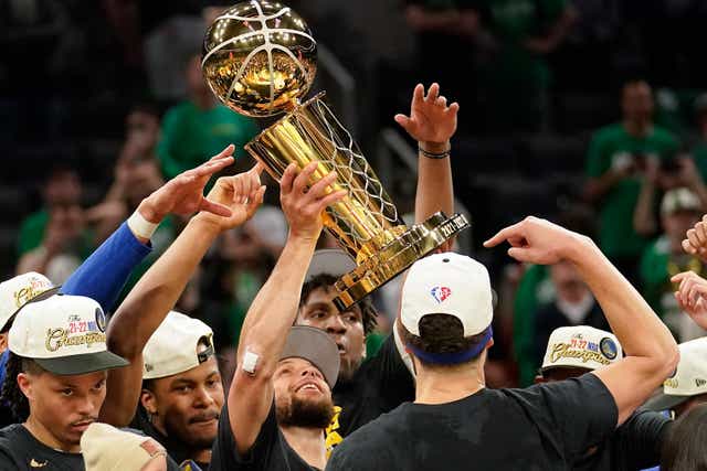 Golden State Warriors guard Stephen Curry holds up the Larry O’Brien Championship Trophy with teammates after defeating the Boston Celtics in Game 6 of basketball’s NBA Finals (Steven Senne/AP)