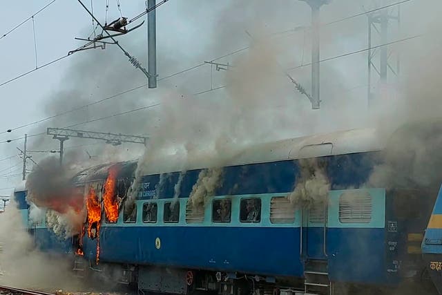 <p>Flames rise from a train set on fire by protestors in Patna, India on 16 June</p>