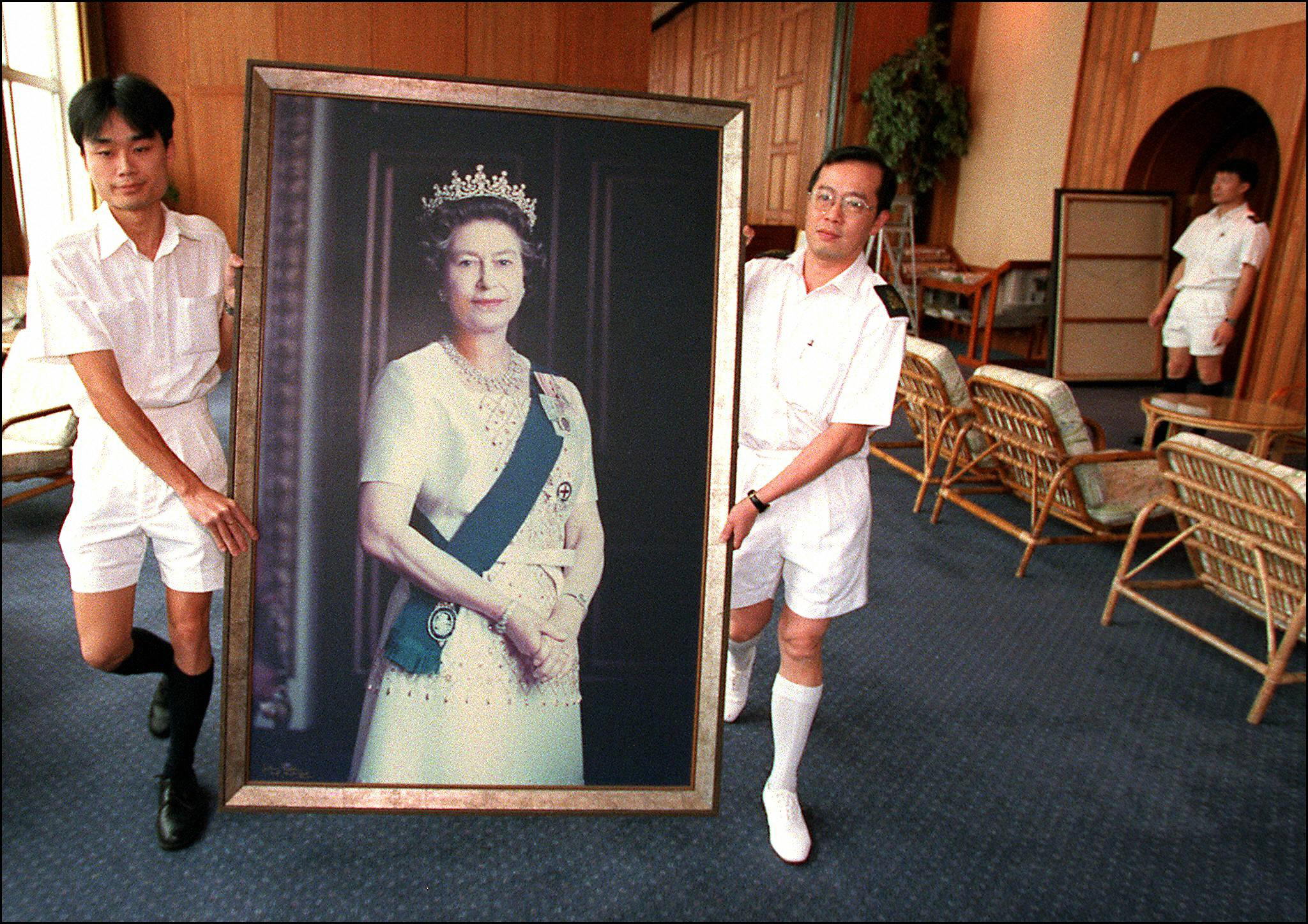 Two Royal Navy sailors carry a portrait of Queen Elizabeth II through the British forces’ Hong Kong headquarters