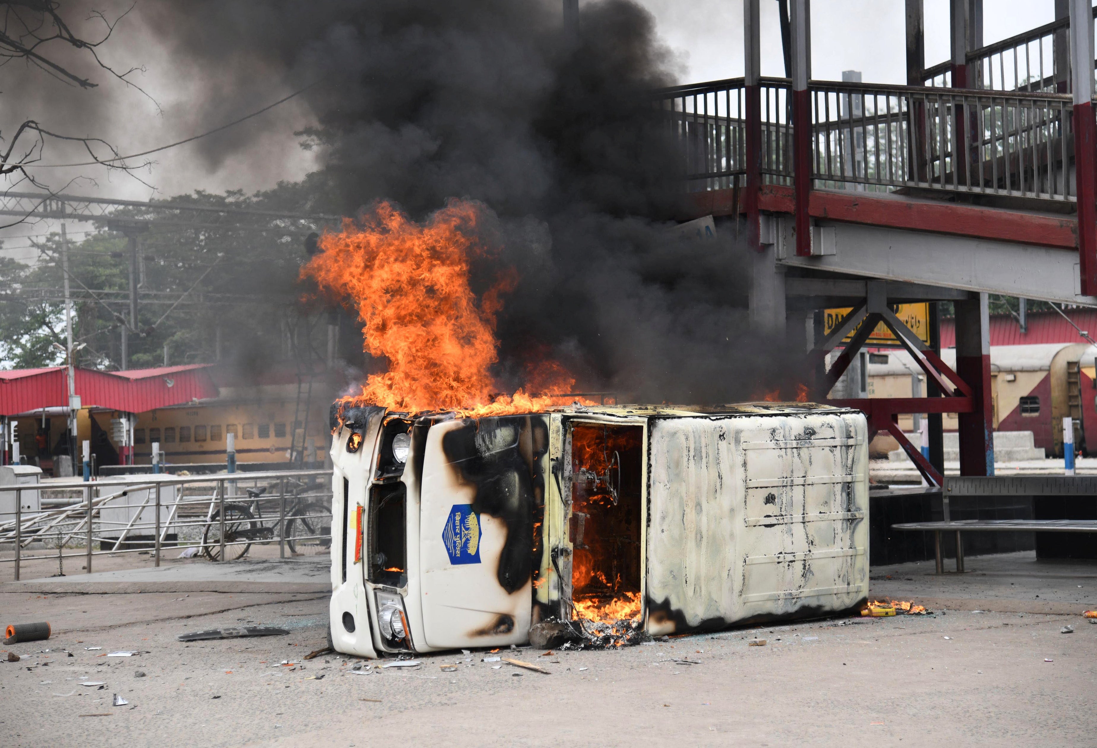 A police vehicle burns after it was set on fire by the protestors during a protest against ‘Agnipath’ in Patna city