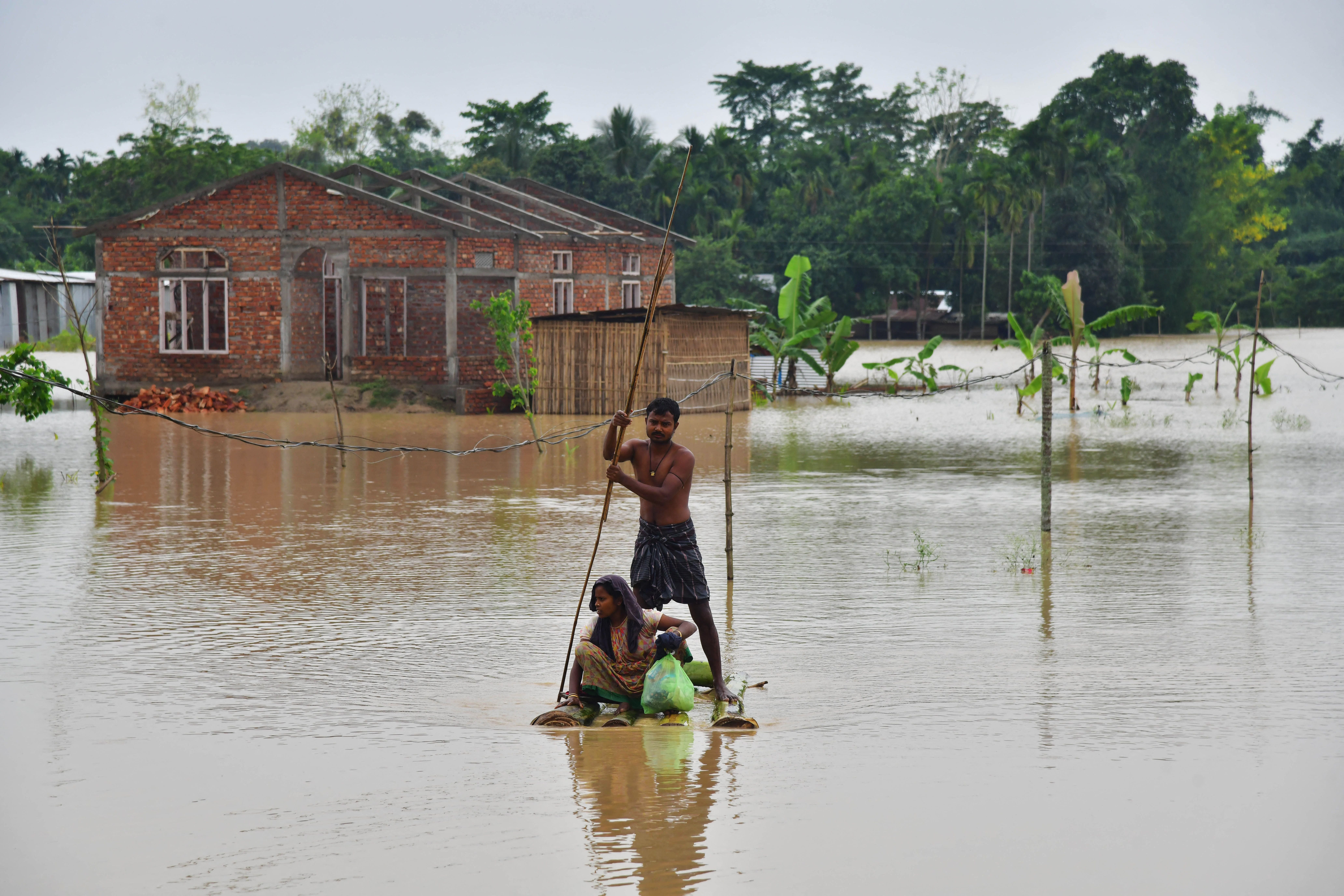 Villagers on a raft make their way past homes in a flooded area after heavy rains in Nagaon district, Assam state, on 21 May