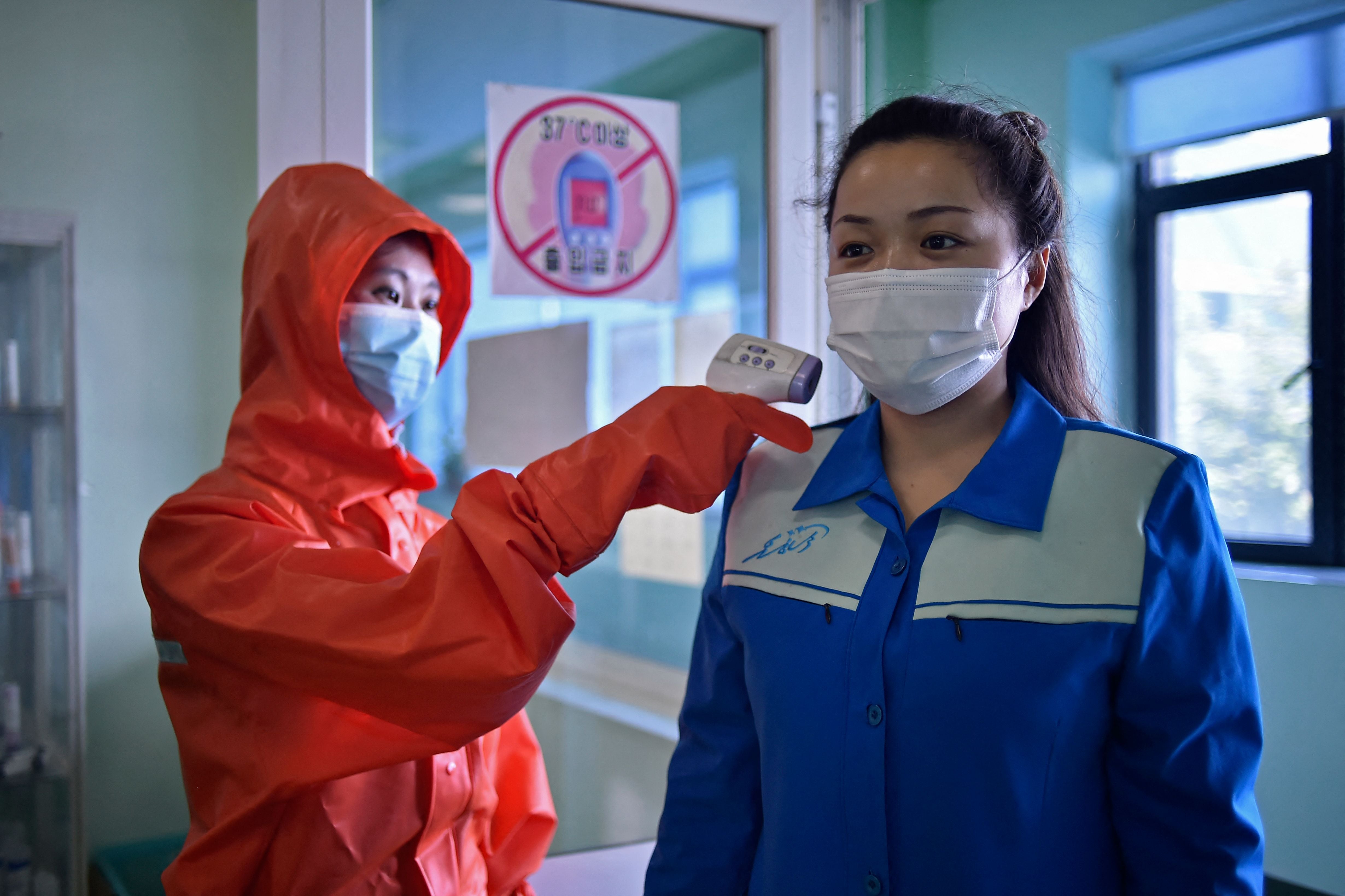<p>A health official takes the temperature of a worker at a factory in Pyongyang on 16 June</p>