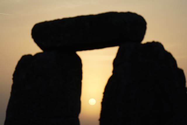 The sun begins to rise behind stones during the Summer Solstice at Stonehenge in Wiltshire (PA)