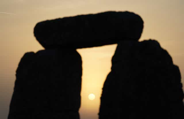 The sun begins to rise behind stones during the Summer Solstice at Stonehenge in Wiltshire (PA)