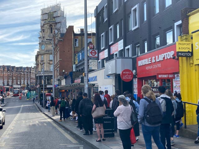 <p>Passengers wait at a bus stop outside Clapham Junction station in southwest London</p>