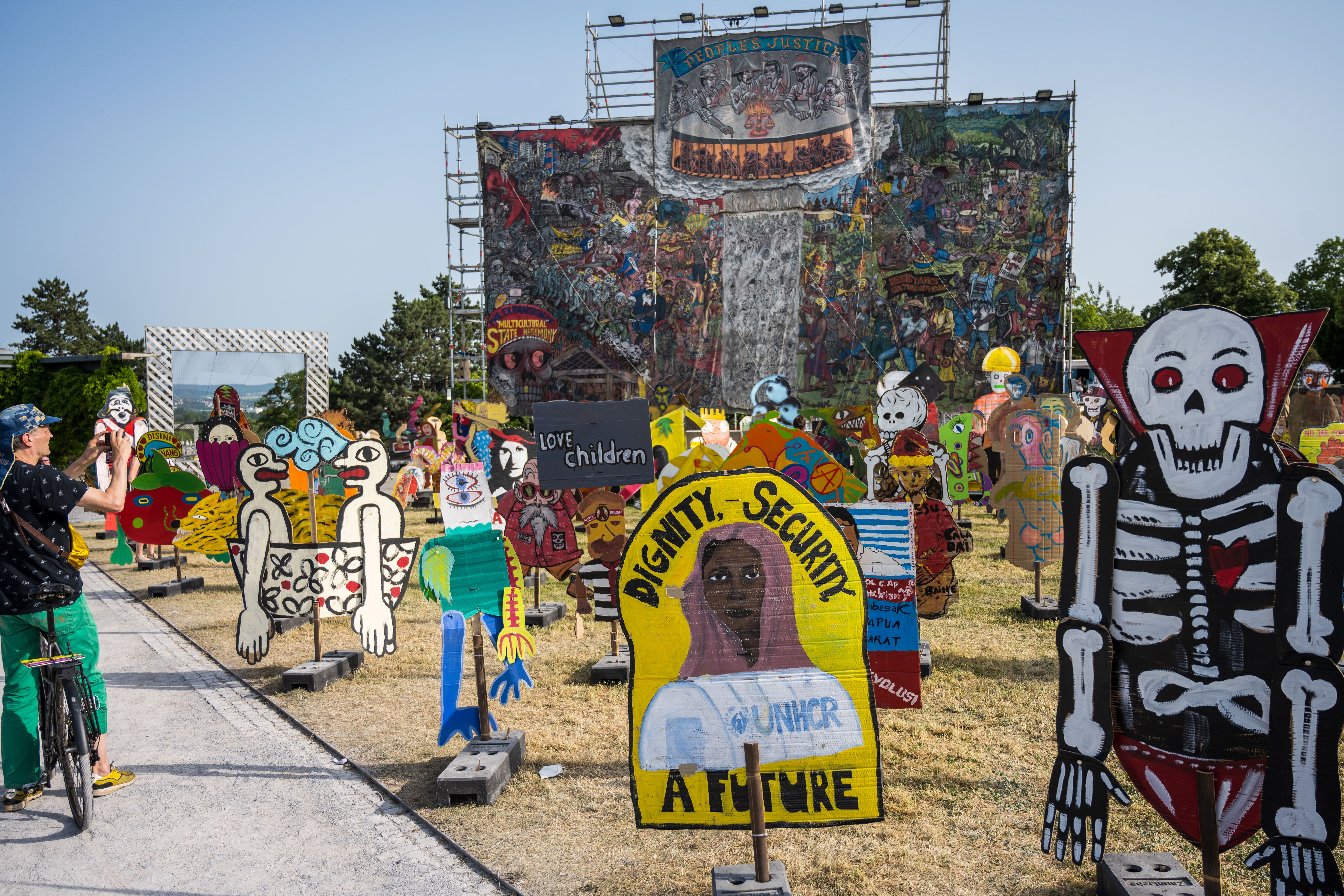 A mural called ‘People’s Justice’ by the Indonesian artists group Taring Padi hangs behind cardboard figures at a modern art fair on June 18 in Kassel, Germany