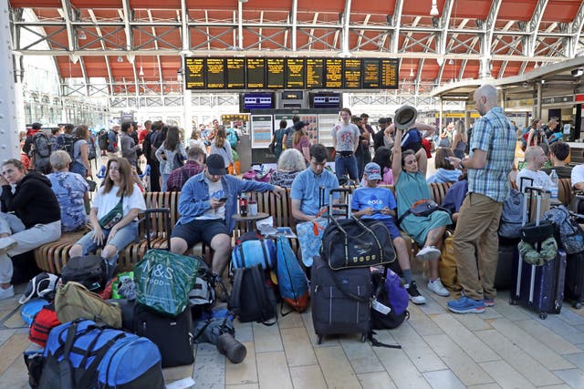 Passengers bound for the Glastonbury Festival wait at Paddington station in London (Ashlee Ruggels/PA)