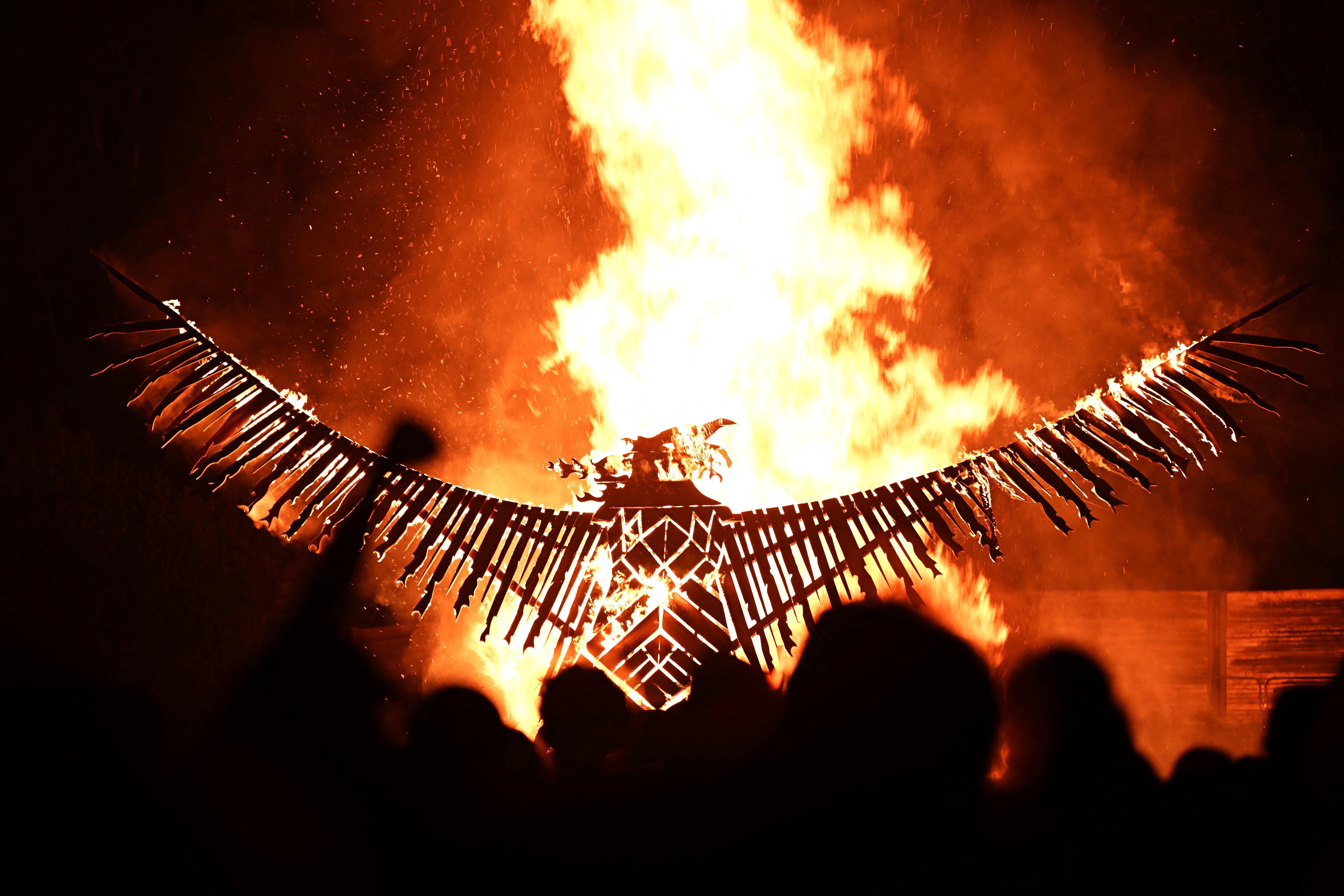 Revellers cheer as a wooden phoenix is burned