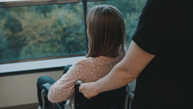 Carer and young woman in a wheelchair on the balcony. (Camera Craft/Alamy Stock Photo)