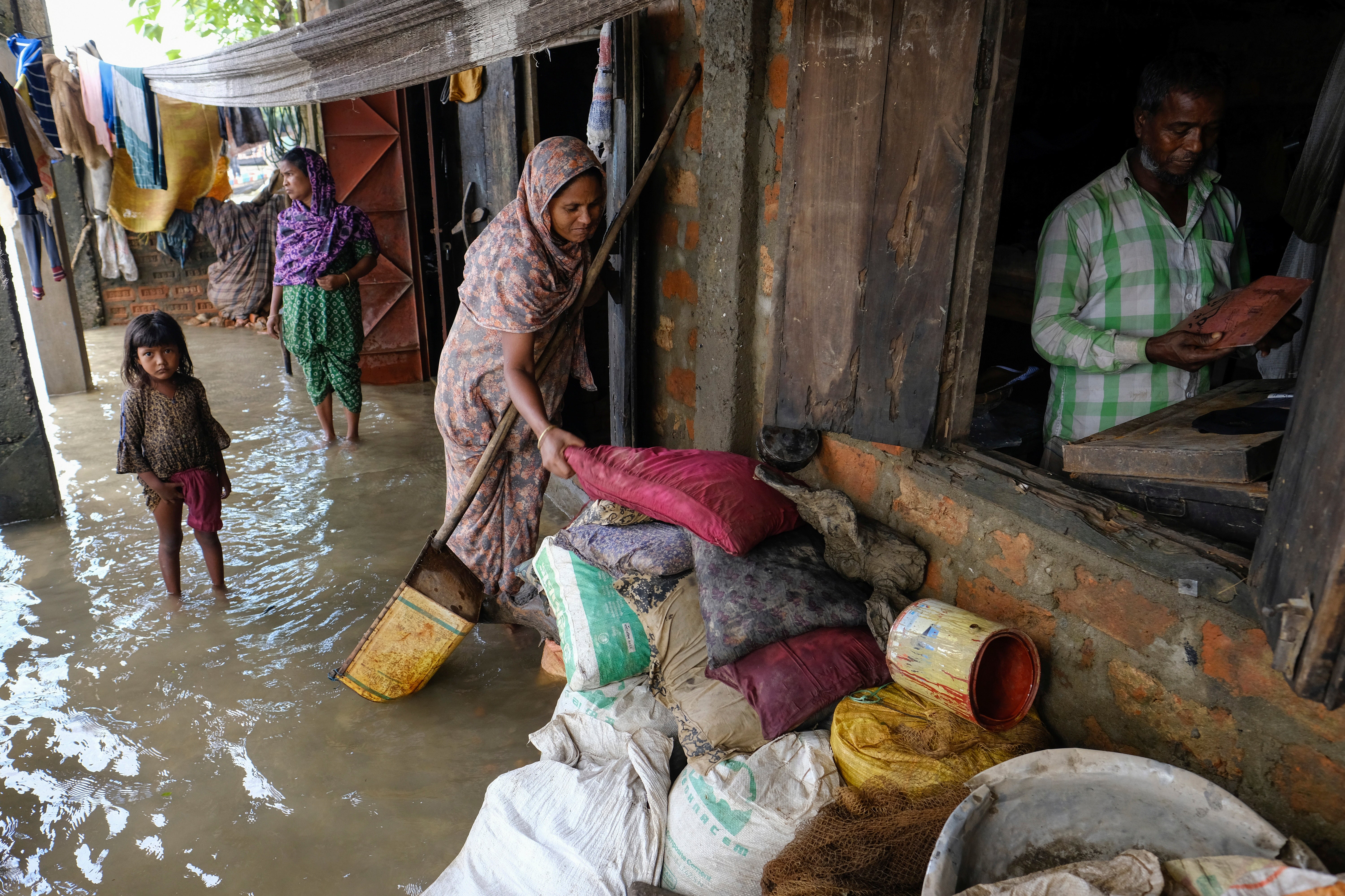 People inspect damaged belongings in their homes as flood water levels recede in Sylhet, Bangladesh in 2022